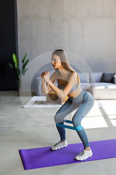 Young woman during her fitness workout at home with rubber resistance band