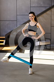 Young woman during her fitness workout at home with rubber resistance band