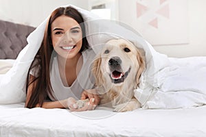 Young woman and her Golden Retriever dog on bed