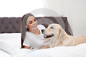 Young woman and her Golden Retriever dog on bed