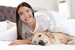 Young woman and her Golden Retriever dog on bed