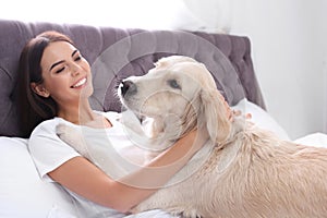 Young woman and her Golden Retriever dog on bed