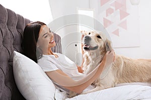 Young woman and her Golden Retriever dog on bed