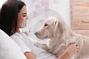 Young woman and her Golden Retriever dog on bed