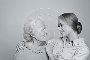 Young woman and her grandmother on light background. Black and white photography