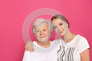 Young woman and her grandmother on pink