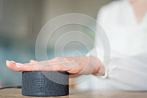 Young woman with her hand turns on the voice assistant in the kitchen copyspace. Smart home technology