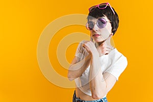 Young woman with her hands crossed under her chin wearing two pairs of sunglasses