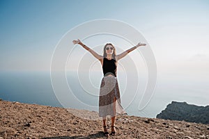 A young woman with her hands up in the fresh air against the background of the sea.