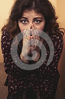 Young woman with her hands up to her face covering her mouth.