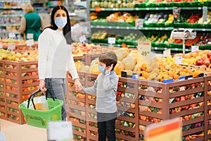 Young woman and her kid wearing protective face masks shop a food at a supermarket during the coronavirus epidemic or