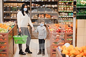 Young woman and her kid wearing protective face masks shop a food at a supermarket during the coronavirus epidemic or