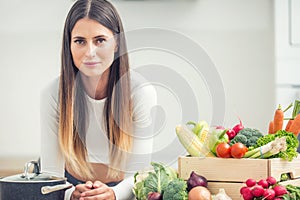 Young woman in her kitchen with fresh organic vegetable looking into the camera