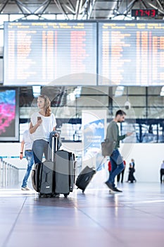 Young woman with her luggage at an international airport, before going through the check-in