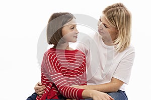 A young woman with her teenage daughter hugs and looks at each other with tenderness. White background