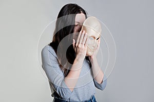 A young woman hides her face behind a mask, the concept of cosmetology