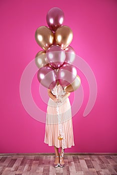 Young woman hiding behind air balloons