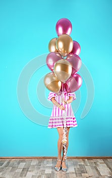 Young woman hiding behind air balloons