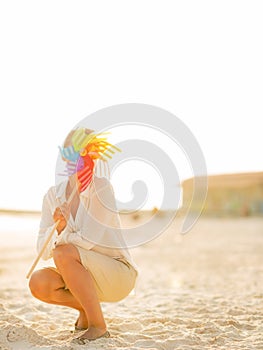 Young woman hiding behind colorful windmill toy