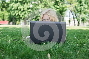 Young woman hiding behind a laptop