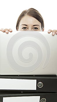 Young woman is hiding behind laptop and documents