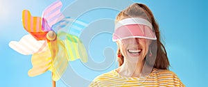 Young woman hiding behind sun visor holding colorful windmill