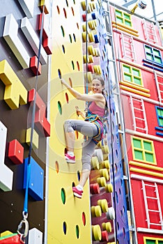 Young woman on high rock-climbing wall