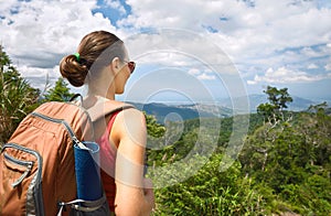 Young woman hiker with backpack enjoying mountains view.
