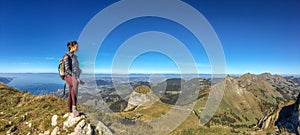 Young woman hiker with backpack on a mountain top against sky background. Travel concept