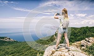 Young woman hiker with backpack standing on a cliff