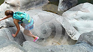 Young woman hiker climbing rock on mountain while summer hiking. Traveling woman with backpack hiking in mountain