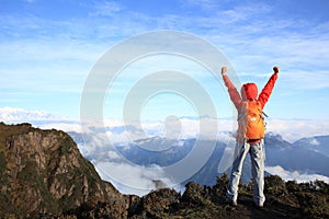 Young woman hiker open arms at mountain peak