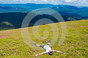 Young woman hiker relaxing on the top of hill and admiring beautiful mountain valley view