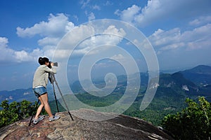 Young woman hiker taking photo with dslr camera