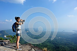 Young woman hiker taking photo with dslr camera