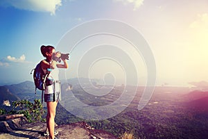 Young woman hiker taking photo with dslr camera