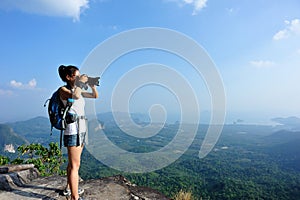 Young woman hiker taking photo with dslr camera