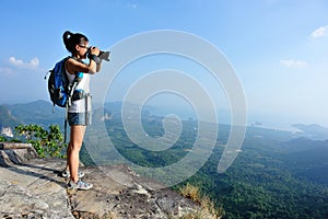 Young woman hiker taking photo with dslr camera