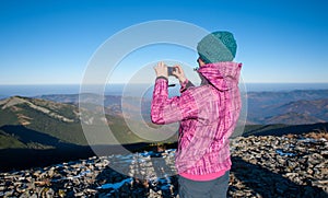 Young woman hiker taking picture with her smartphone