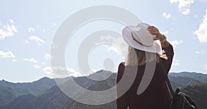 Young woman hiker tourist in hat admiring amazing view in mountains valley.