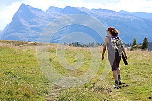 Young woman hiker walks in the high mountain trail in the Italian Alps on the Dolomites mountain range