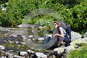 Mladá žena pěší turistiku a přestávku u horské bystřiny