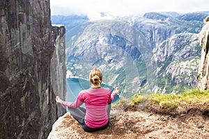 Young woman hiking on kjerag. Happy girl enjoy beautiful lake and good weather in Norway