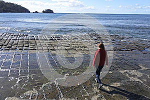 Young woman hiking over the Tessellated Pavement in Tasman Peninsula Tasmania Australia photo