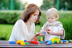 Young woman with his toddler son playing with colorful plastic blocks