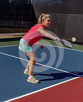 Young woman hits a pickleball with a backhand volley