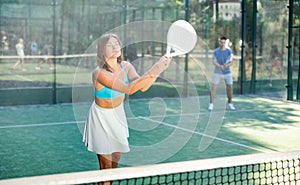 Young woman hitting two handed backhand during paddle tennis match