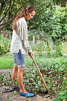 Young woman with hoe working in the garden