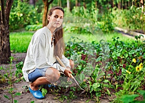 Young woman with hoe working in the garden bed