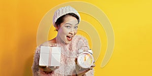 Young woman holding a alarm clock showing nearly 12